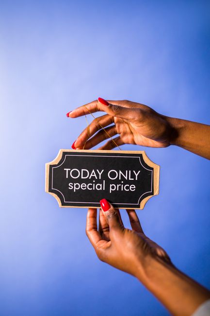 A pair of hands with neatly manicured nails painted red are holding a small, rectangular blackboard sign with a decorative border. The sign displays the message 'TODAY ONLY special price' in white uppercase and lowercase letters. The person's right hand is grasping the sign from below while their left hand is delicately holding a thin string attached to the top of the sign, gently lifting it against a plain, evenly lit blue background. The scene emphasizes the promotional message, which could relate to special offers for rubbish removal services, while the neutral setting maintains a professional tone. The focus on the hands and sign highlights the concept of a limited-time deal, aligning with the idea of promotional or alternative waste handling options, such as private rubbish collection or on-site clearance, relevant to the context of waste removal providers like Waste Removal Paddington.